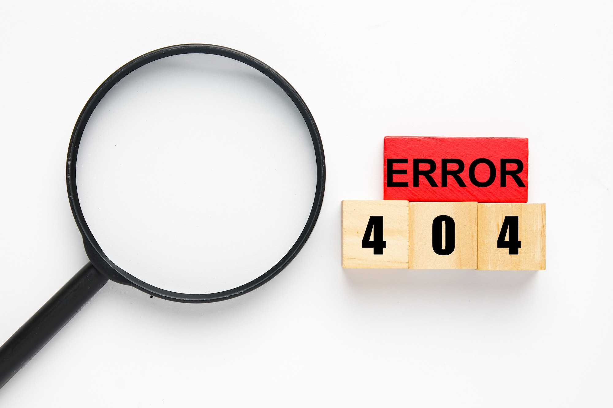 Magnifying glass, wooden block red and brown with the word Error 404. Try and error concept